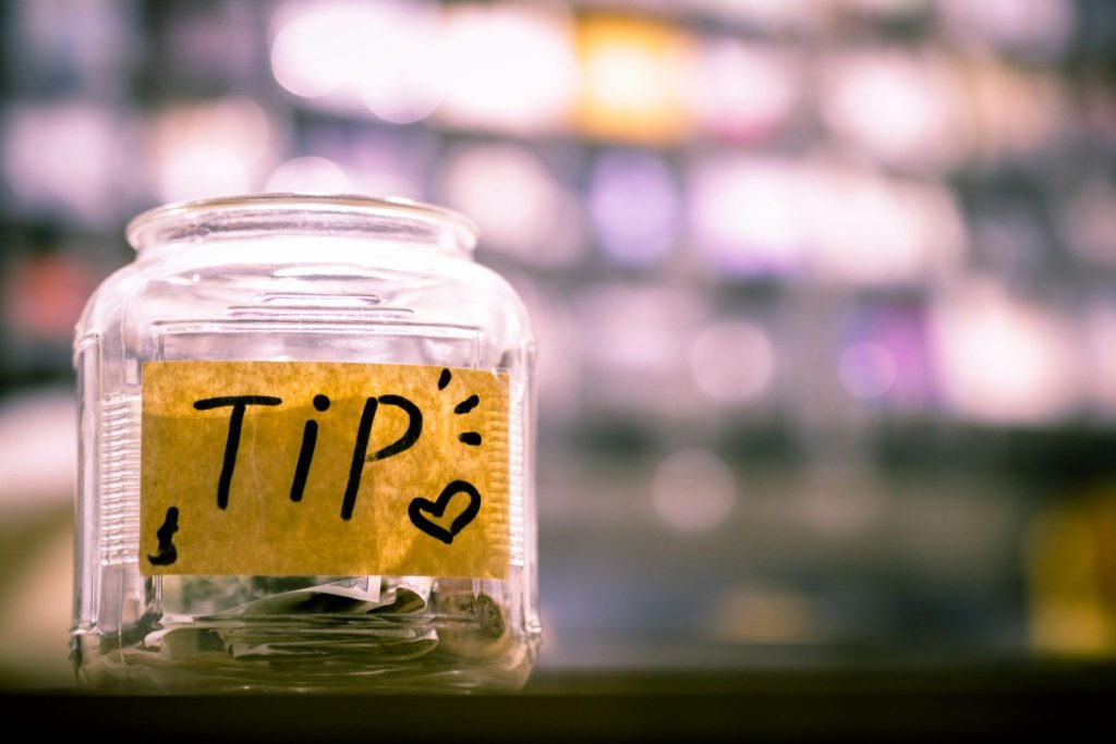 Glass tip jar with handwritten tip sign