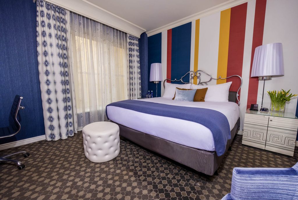 The Marker San Francisco guest room with colorful striped accent wall and king bed.