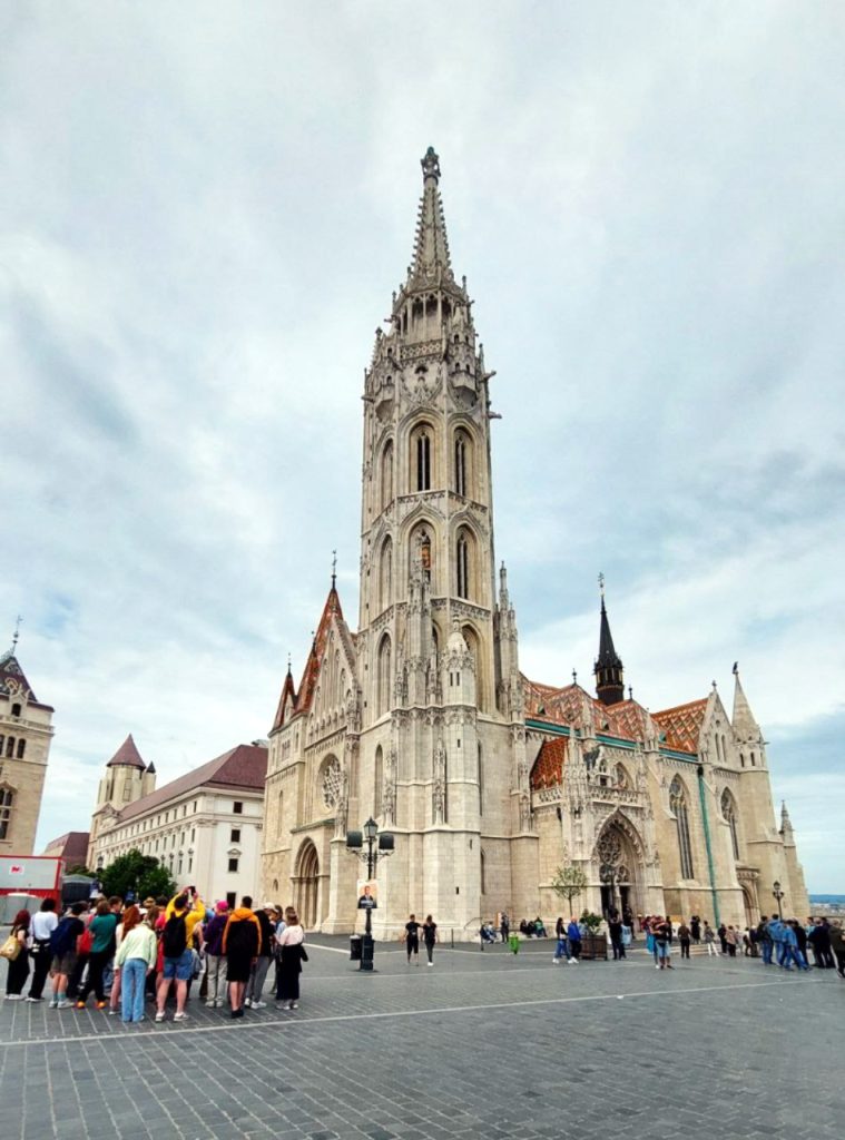 Gothic-style church with a tall central tower and crowds of visitors in front.