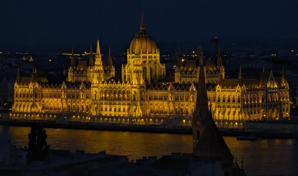 Hungarian Parliament building illuminated at night, reflected in the Danube River