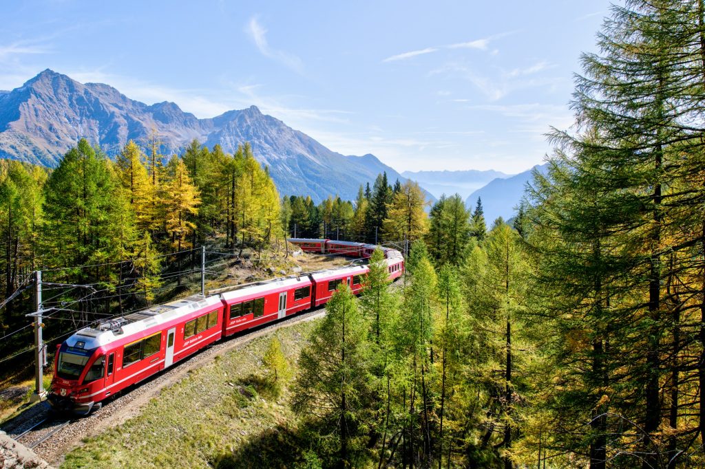 Swiss red train passing through Alpine landscape